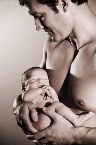 Close-up of bare-chested man holding newborn baby in arms